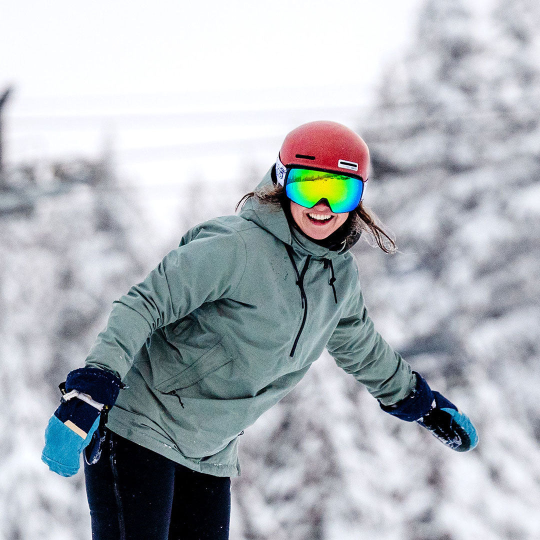 Snowboarder wearing reflective goggles and a leopard print jacket in snowy landscape.