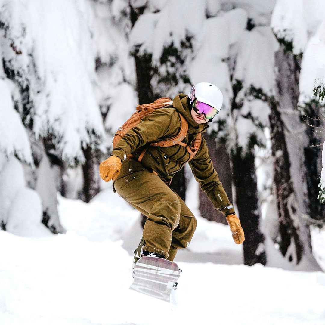 Ski goggles with purple lens on a snowboard with a neon green strap.