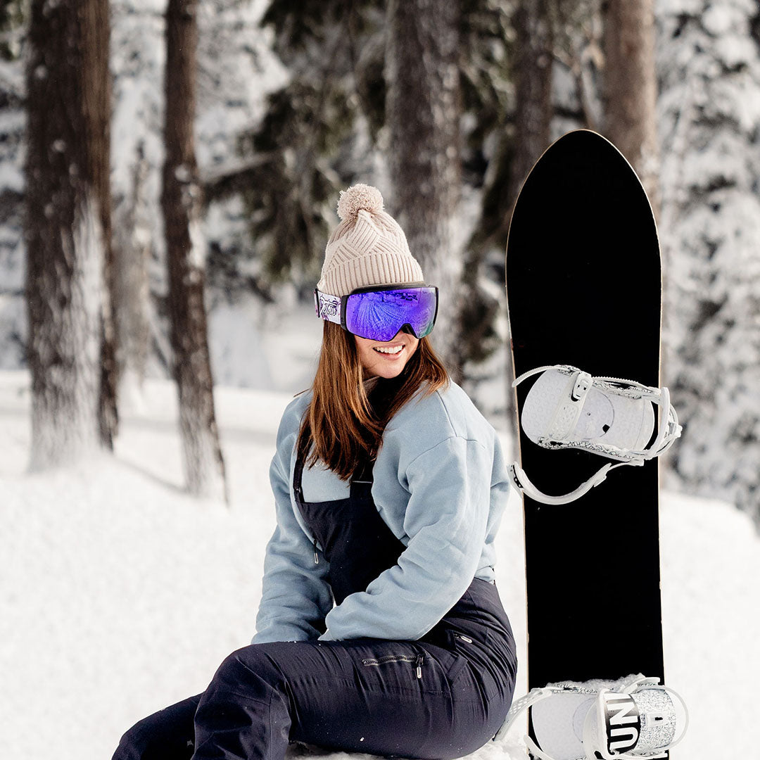 Person wearing pink ski goggles and a black beanie in snowy conditions.